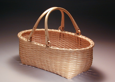 Double Swing Handle Oval Carrier - rectangular bottom to oval top carrier basket with two bent loop swing handles. Hand woven of brown (black) ash. Hand crafted by Stephen Zeh, Maine basketmaker