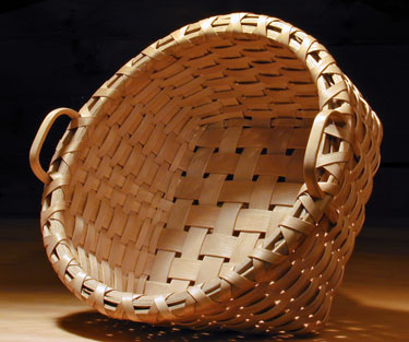 Bread Basket - side view. Square bottom to round top basket with two hand carved side handles. Handcrafted of brown / black ash  by Stephen Zeh, Maine basket maker.