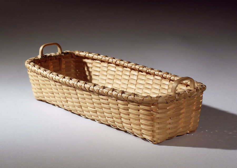 Cracker Basket - a rectangular basket with two hand carved end handles. It is sized to fit a stack of crackers. Hand crafted of brown ash by Maine basket maker Stephen Zeh.