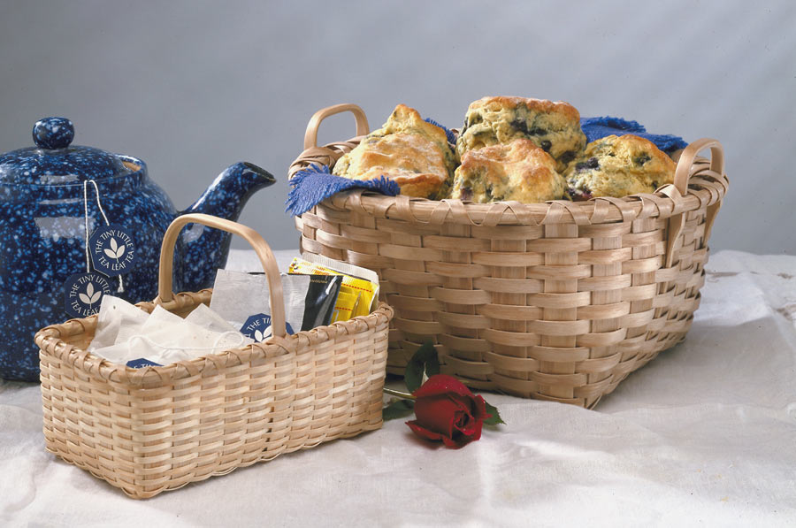 Tea Basket and Bread Basket with teapot setting on white table cloth  with a rose. 