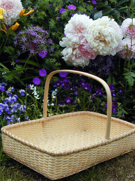 Sweetgrass Flower Tray in the garden with peonies and summer flowers hand crafted of brown or black ash and sweet grass by Stephen Zeh basket maker of Temple, Maine.